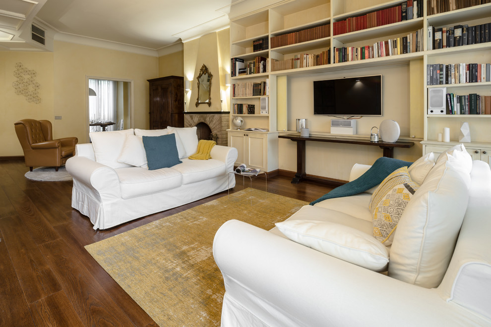 Example of a large classic formal and open concept medium tone wood floor and brown floor living room design in Milan with yellow walls, a standard fireplace, a stone fireplace and a concealed tv