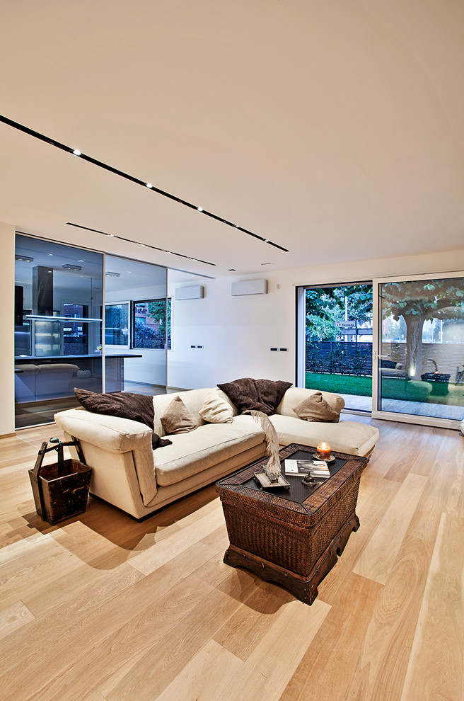 Foto de salón abierto actual grande con paredes blancas y suelo de madera clara