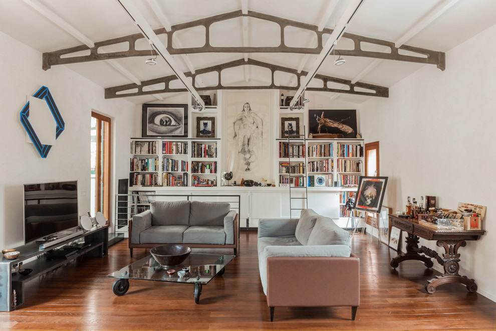 Imagen de sala de estar con biblioteca cerrada industrial de tamaño medio con paredes blancas, televisor independiente, suelo marrón y suelo de madera en tonos medios