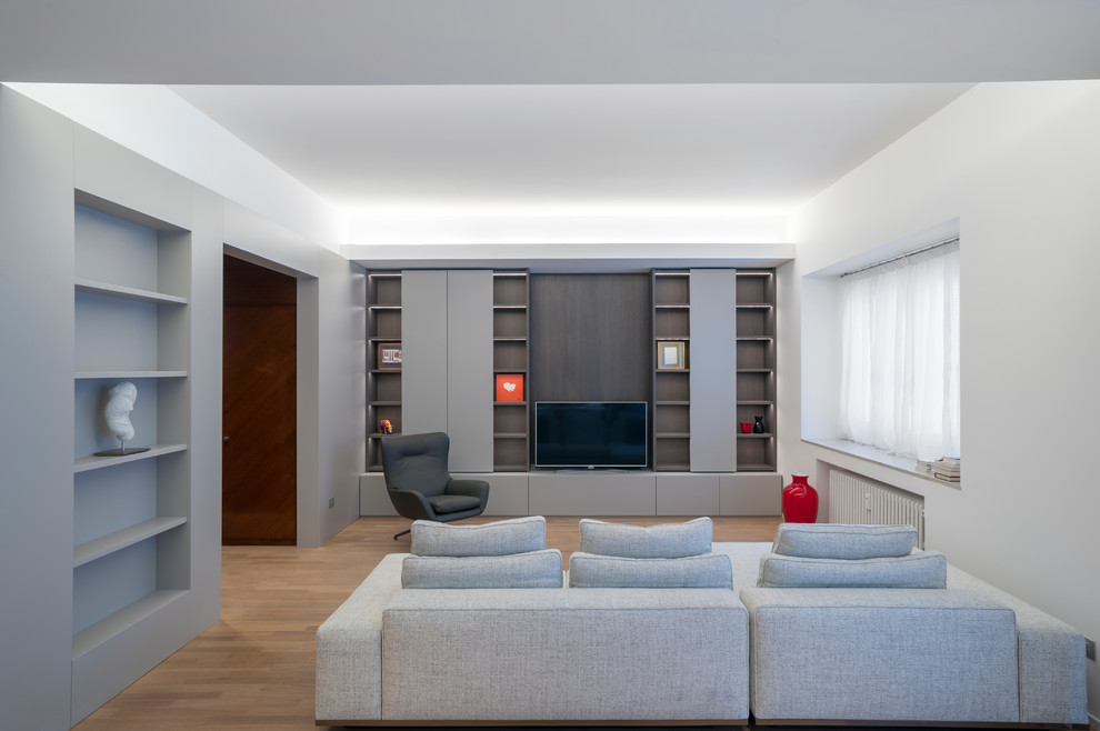 Cette image montre un salon minimaliste de taille moyenne et ouvert avec un mur gris, un sol en bois brun et un téléviseur fixé au mur.