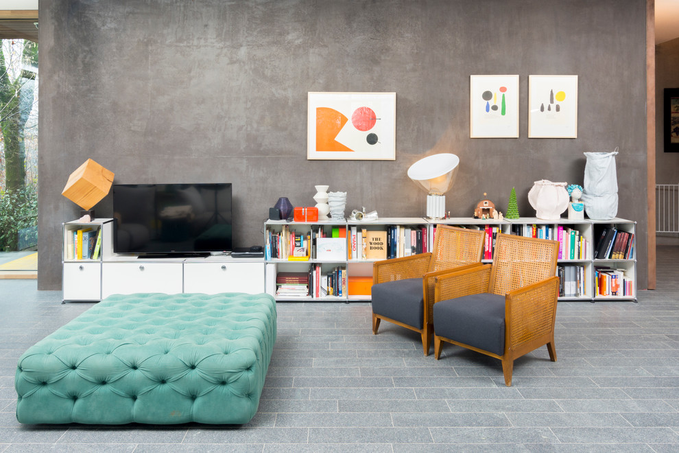 На фото: открытая гостиная комната среднего размера в стиле фьюжн с с книжными шкафами и полками, серыми стенами, отдельно стоящим телевизором, полом из известняка и серым полом