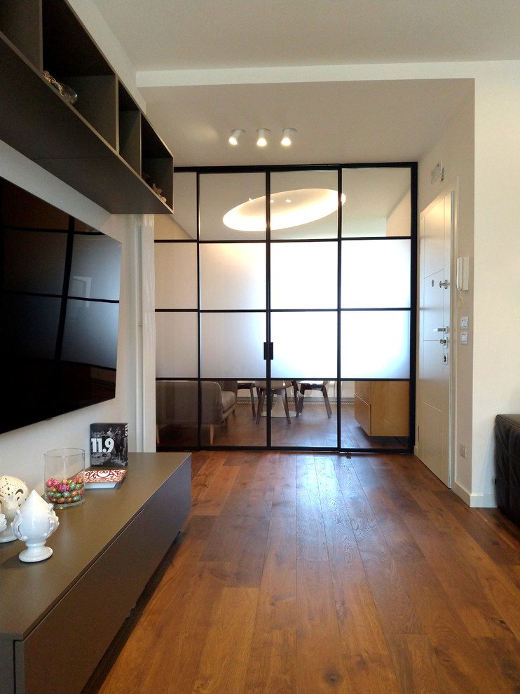 Пример оригинального дизайна: большая открытая гостиная комната в стиле лофт с белыми стенами, темным паркетным полом и телевизором на стене
