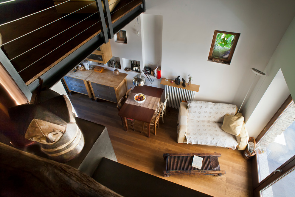 На фото: открытая гостиная комната среднего размера в стиле кантри с деревянным полом и печью-буржуйкой