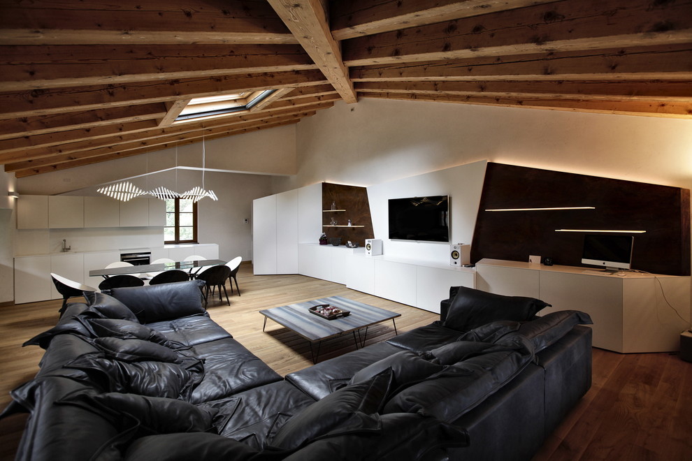Пример оригинального дизайна: гостиная комната в современном стиле с белыми стенами, паркетным полом среднего тона и телевизором на стене