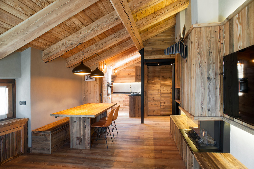 Diseño de salón abierto rural grande con televisor colgado en la pared, suelo de madera en tonos medios, marco de chimenea de madera, chimenea de doble cara y paredes beige