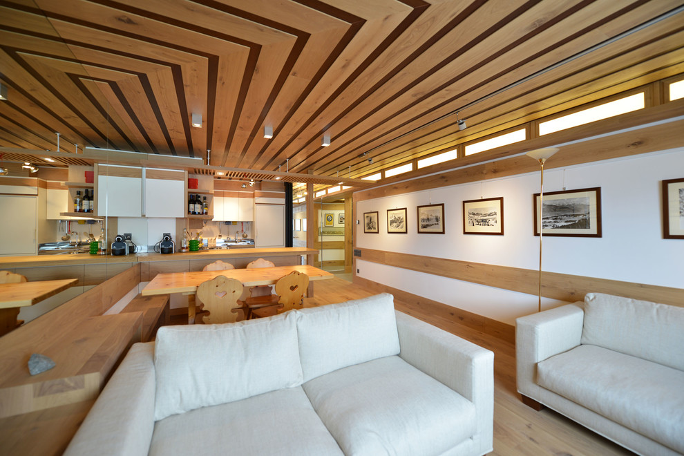 Modelo de salón cerrado rústico de tamaño medio sin chimenea con paredes blancas, suelo de madera clara y pared multimedia