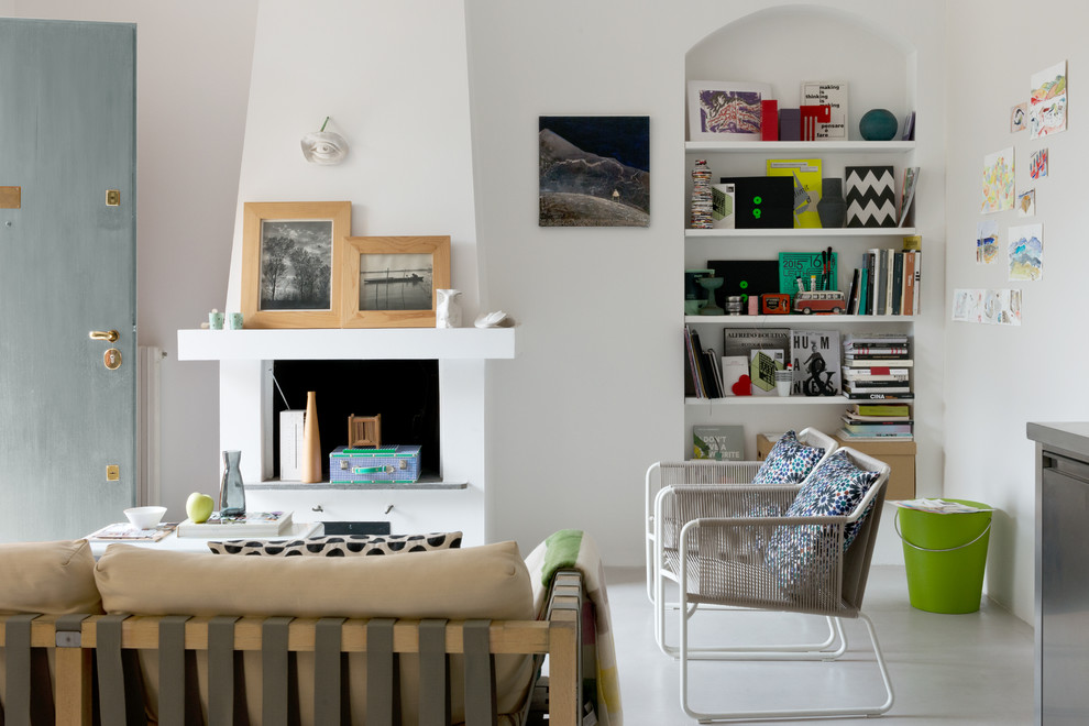 На фото: маленькая открытая гостиная комната в современном стиле с белыми стенами, бетонным полом, стандартным камином, фасадом камина из штукатурки и серым полом для на участке и в саду