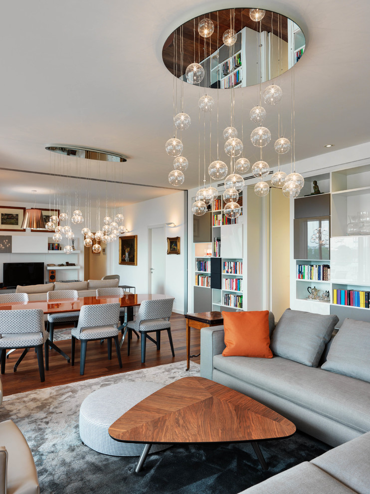 Esempio di un soggiorno design aperto con libreria, pareti bianche, pavimento in legno massello medio, TV autoportante e pavimento marrone