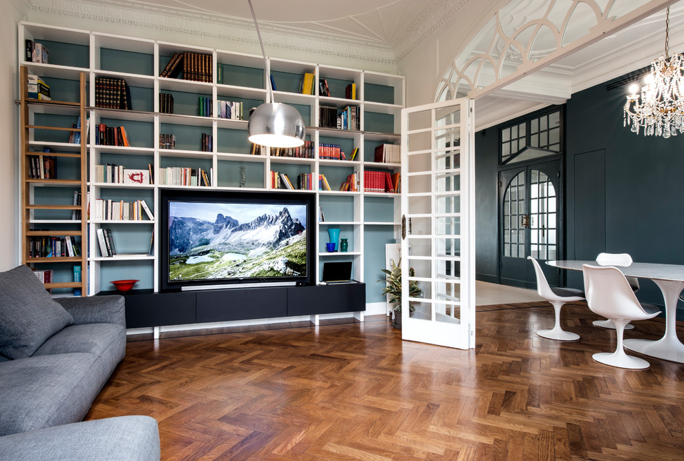 Idee per un soggiorno chic di medie dimensioni e aperto con libreria, pareti blu, parquet chiaro e parete attrezzata