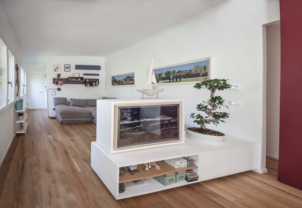 Imagen de salón abierto contemporáneo de tamaño medio con paredes multicolor, suelo de madera en tonos medios, televisor retractable y suelo beige