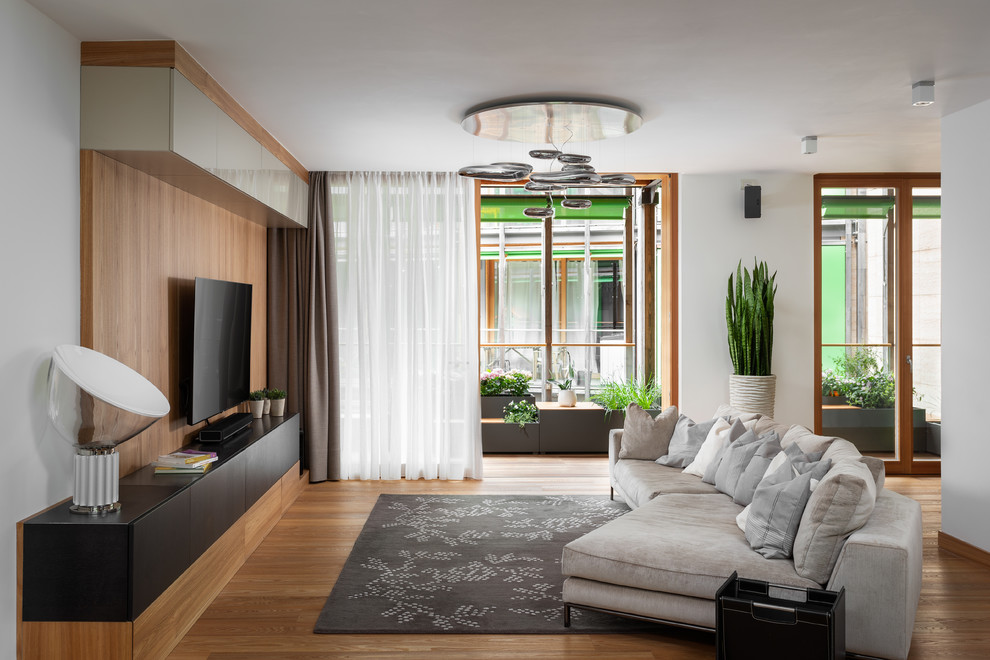 Diseño de sala de estar abierta contemporánea con suelo de madera en tonos medios y televisor colgado en la pared
