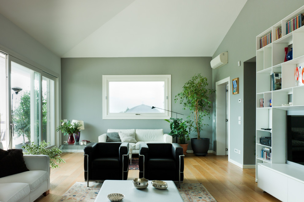 Idee per un grande soggiorno minimal con TV a parete, pareti verdi e parquet chiaro