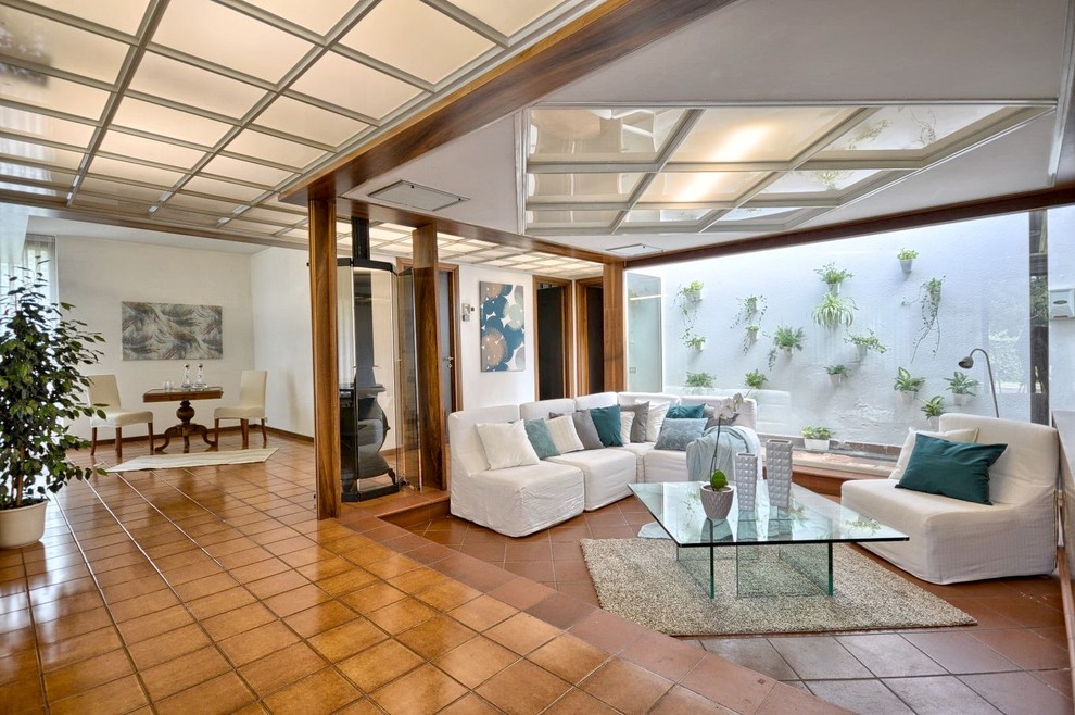 Foto på ett stort funkis allrum med öppen planlösning, med en hemmabar, vita väggar, klinkergolv i terrakotta, en öppen vedspis, en spiselkrans i metall och brunt golv