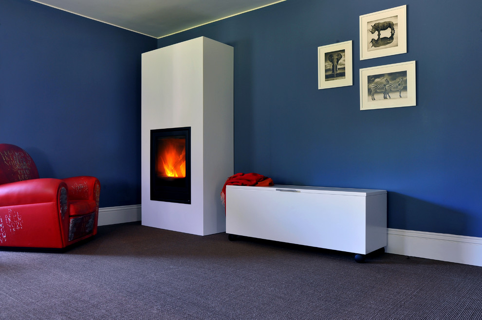 Foto de sala de estar actual con paredes azules, marco de chimenea de metal, estufa de leña y suelo marrón