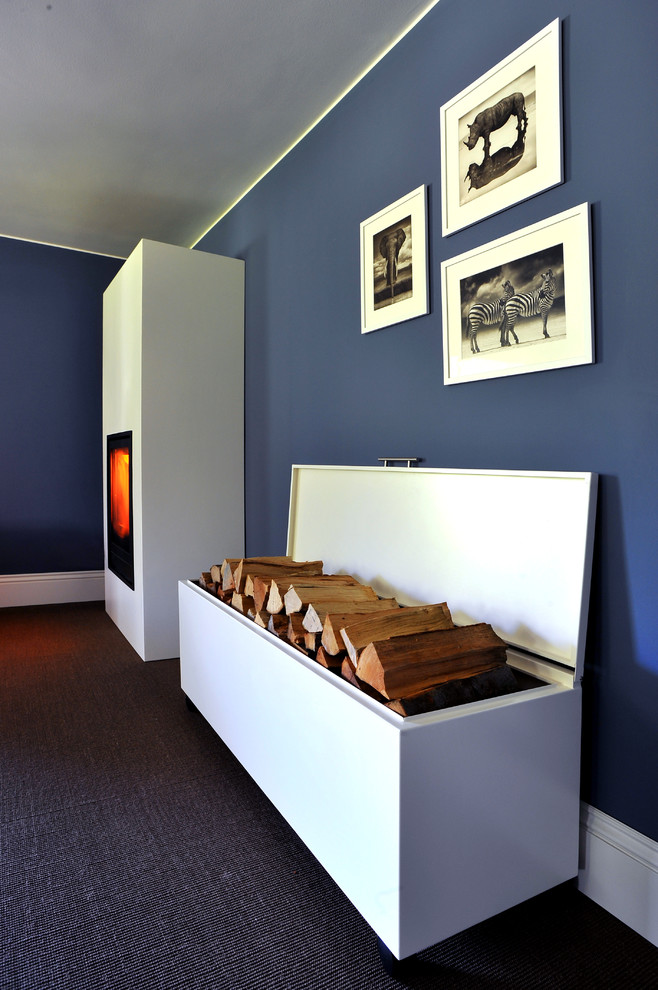 Modelo de sala de estar actual con paredes azules, marco de chimenea de metal, estufa de leña y suelo marrón