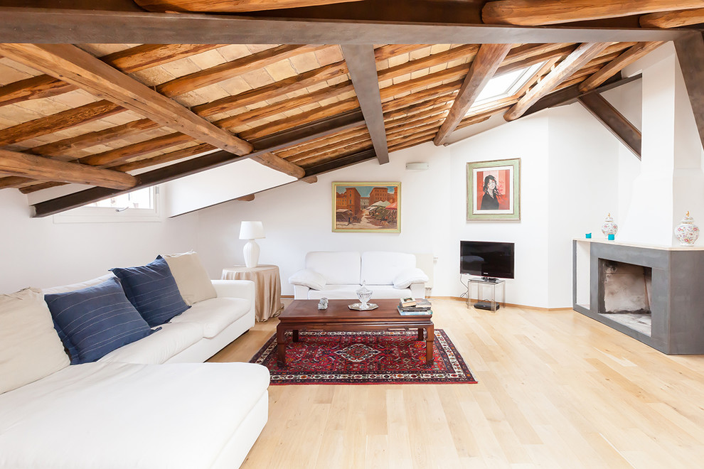 Landhaus Wohnzimmer mit weißer Wandfarbe, hellem Holzboden und freistehendem TV in Rom