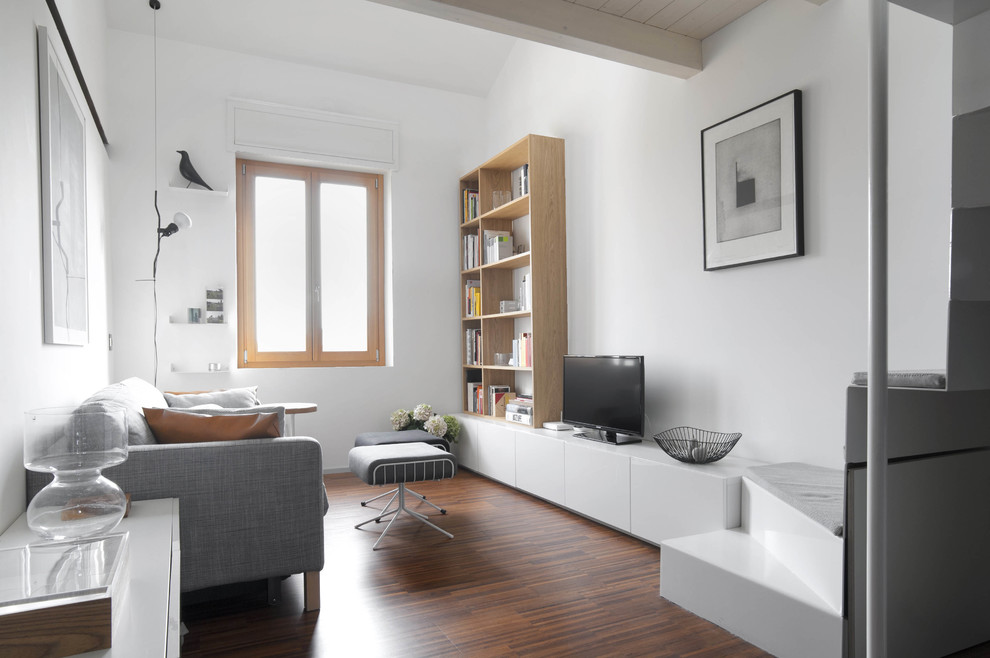 На фото: открытая гостиная комната в скандинавском стиле с белыми стенами, темным паркетным полом и отдельно стоящим телевизором с