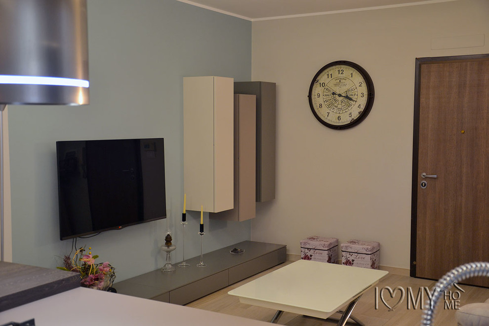 Immagine di un grande soggiorno minimalista aperto con pareti multicolore, parquet chiaro e TV a parete