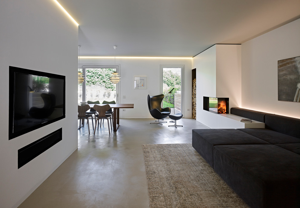 Imagen de salón abierto actual con paredes blancas, chimenea de esquina y televisor colgado en la pared