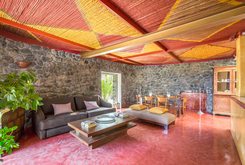 Diseño de salón abierto ecléctico con suelo rojo, paredes grises y piedra