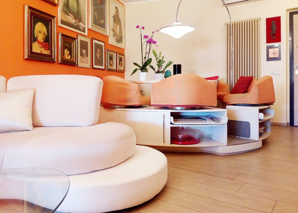 На фото: большая открытая гостиная комната в стиле фьюжн с оранжевыми стенами, полом из керамогранита, телевизором на стене и бежевым полом без камина