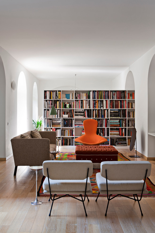 Immagine di un soggiorno design con libreria, pareti bianche e parquet chiaro