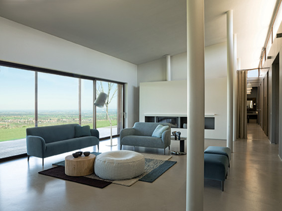 Modelo de sala de estar abierta retro grande con paredes grises, suelo de cemento, chimenea lineal, marco de chimenea de hormigón y suelo gris