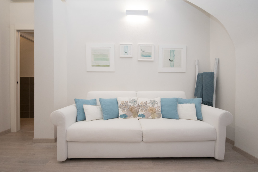 На фото: открытая гостиная комната в средиземноморском стиле с белыми стенами и полом из ламината