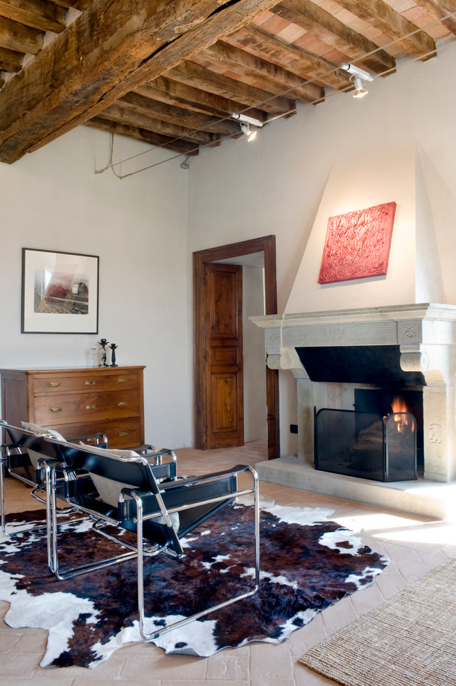 Imagen de sala de estar bohemia con paredes blancas, suelo de baldosas de terracota, todas las chimeneas y marco de chimenea de piedra