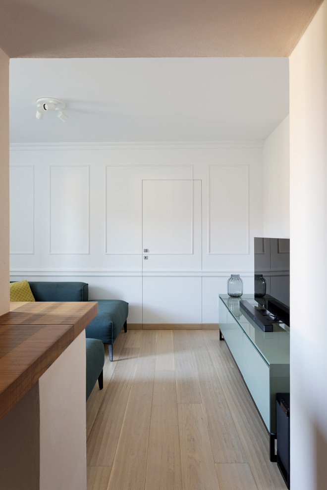 Modelo de sala de estar abierta bohemia pequeña con paredes blancas, suelo de madera clara y televisor independiente