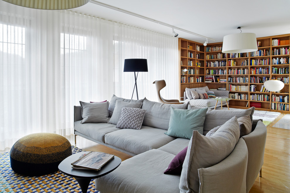 Ispirazione per un soggiorno moderno con libreria, pareti bianche e parquet chiaro
