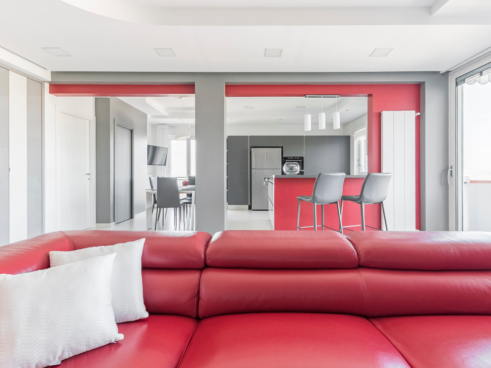 Источник вдохновения для домашнего уюта: большая открытая гостиная комната в стиле модернизм с домашним баром, красными стенами, отдельно стоящим телевизором, полом из керамогранита, горизонтальным камином и серым полом