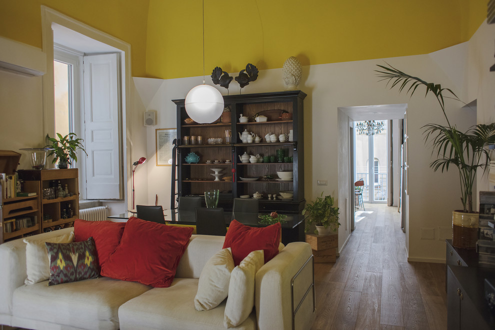 Cette photo montre une salle de séjour tendance de taille moyenne et fermée avec un mur jaune, parquet clair et un sol marron.