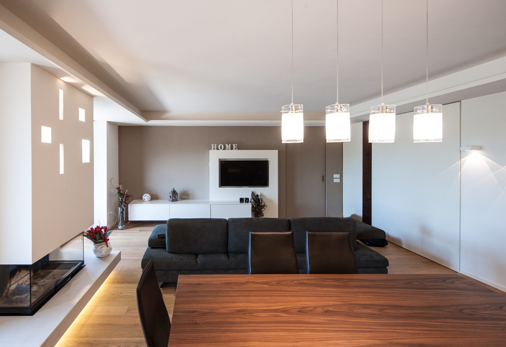 Mittelgroßes, Offenes Modernes Wohnzimmer mit weißer Wandfarbe, hellem Holzboden, verputzter Kaminumrandung, Multimediawand und beigem Boden in Sonstige