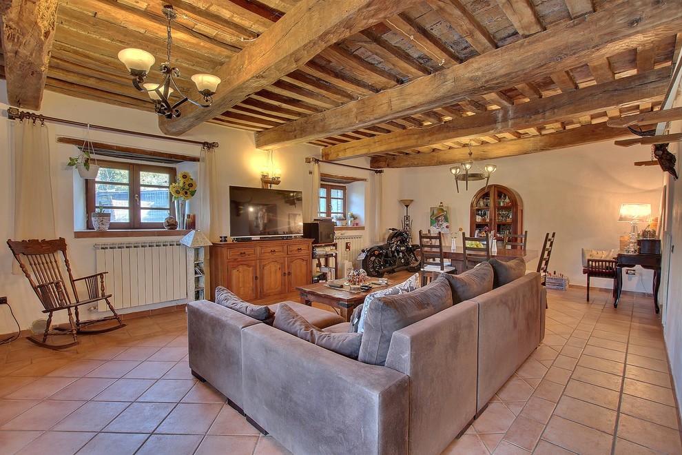 Foto di un soggiorno stile rurale con pareti beige, pavimento in terracotta, TV autoportante e pavimento rosso