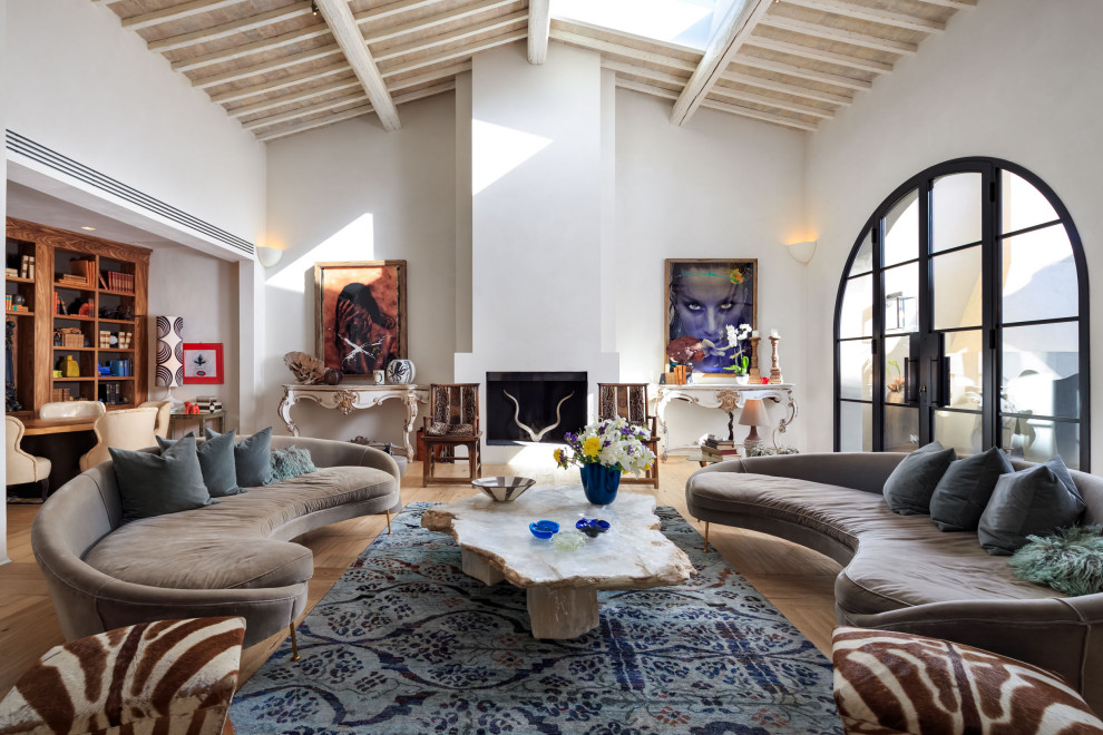This is an example of a mediterranean open plan living room in Florence with white walls, light hardwood flooring, a standard fireplace, beige floors and a vaulted ceiling.