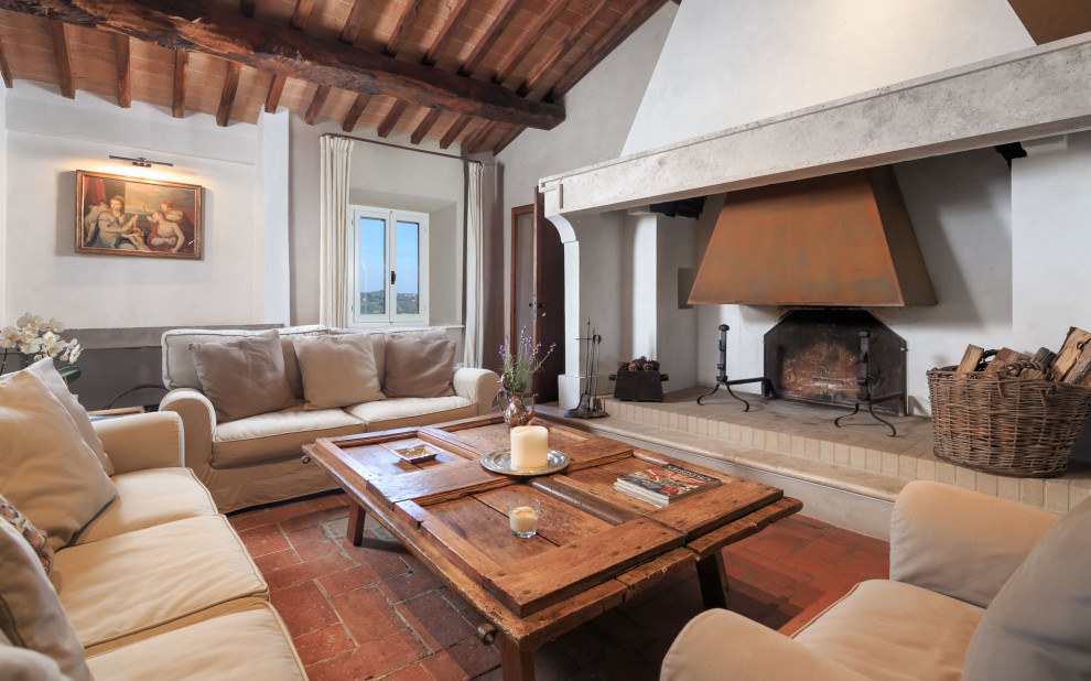 Inspiration for a mediterranean living room in Other with white walls, a standard fireplace, red floors, exposed beams and a vaulted ceiling.