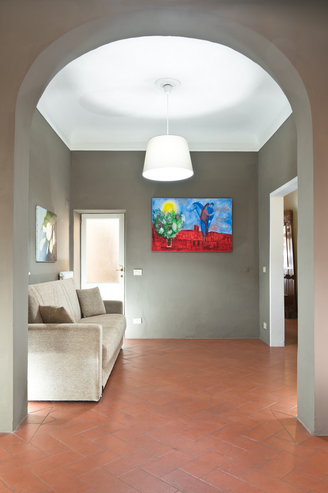 Immagine di un piccolo soggiorno minimalista aperto con pareti grigie, pavimento in terracotta, TV a parete e pavimento arancione