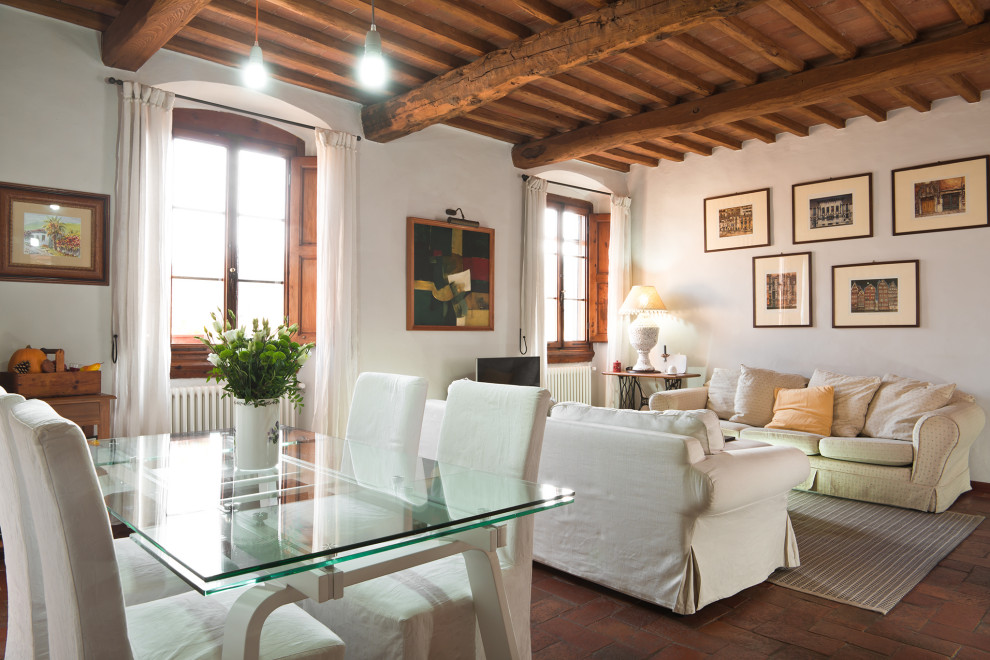 Exemple d'un salon romantique de taille moyenne et fermé avec un mur blanc, tomettes au sol, un poêle à bois, un manteau de cheminée en métal, un téléviseur indépendant et un sol orange.