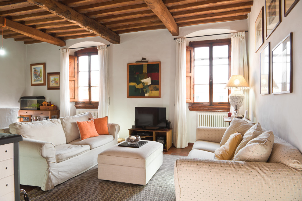 Immagine di un soggiorno mediterraneo di medie dimensioni e chiuso con pareti bianche, pavimento in terracotta, TV autoportante, pavimento arancione e travi a vista
