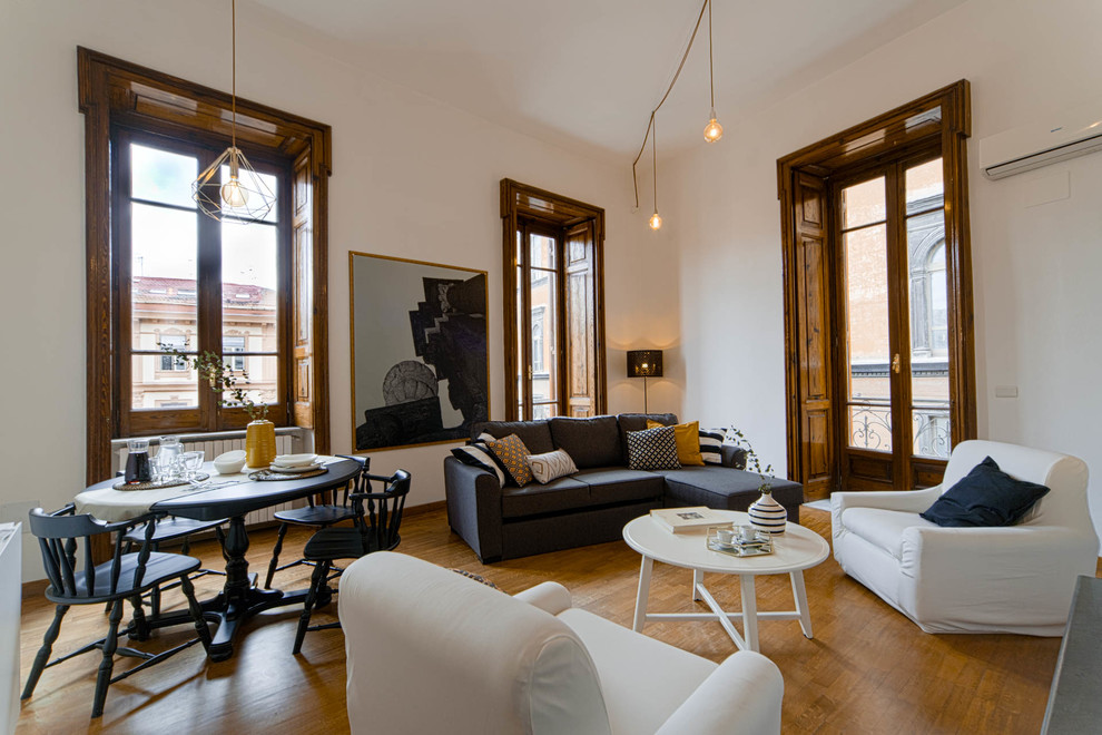 Modelo de salón abierto tradicional renovado con paredes blancas, suelo de madera en tonos medios y suelo marrón