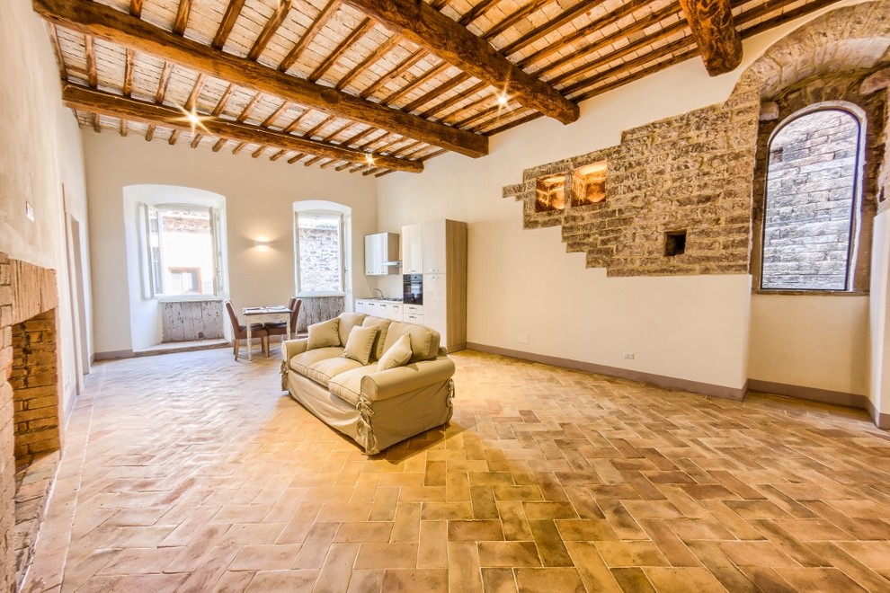 Mittelgroßes, Offenes Mediterranes Wohnzimmer mit Terrakottaboden, Kamin und Kaminumrandung aus Backstein in Sonstige