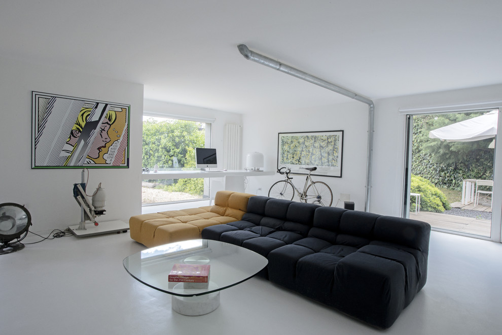 Modelo de sala de estar abierta minimalista de tamaño medio con paredes blancas, suelo de cemento y televisor independiente