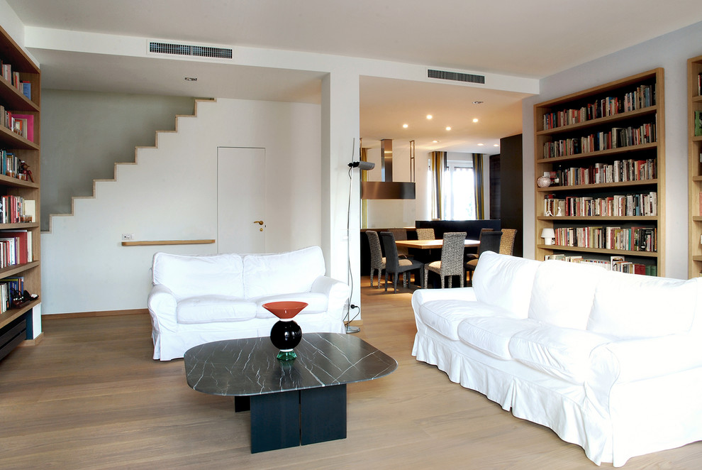 Esempio di un soggiorno contemporaneo di medie dimensioni e aperto con libreria, pareti bianche e parquet chiaro
