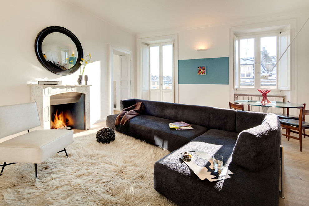 Example of a large trendy enclosed light wood floor family room design in Turin with a standard fireplace and no tv