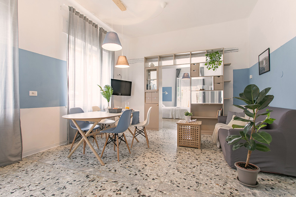Idée de décoration pour une salle de séjour marine avec un mur bleu, un téléviseur d'angle et un sol gris.