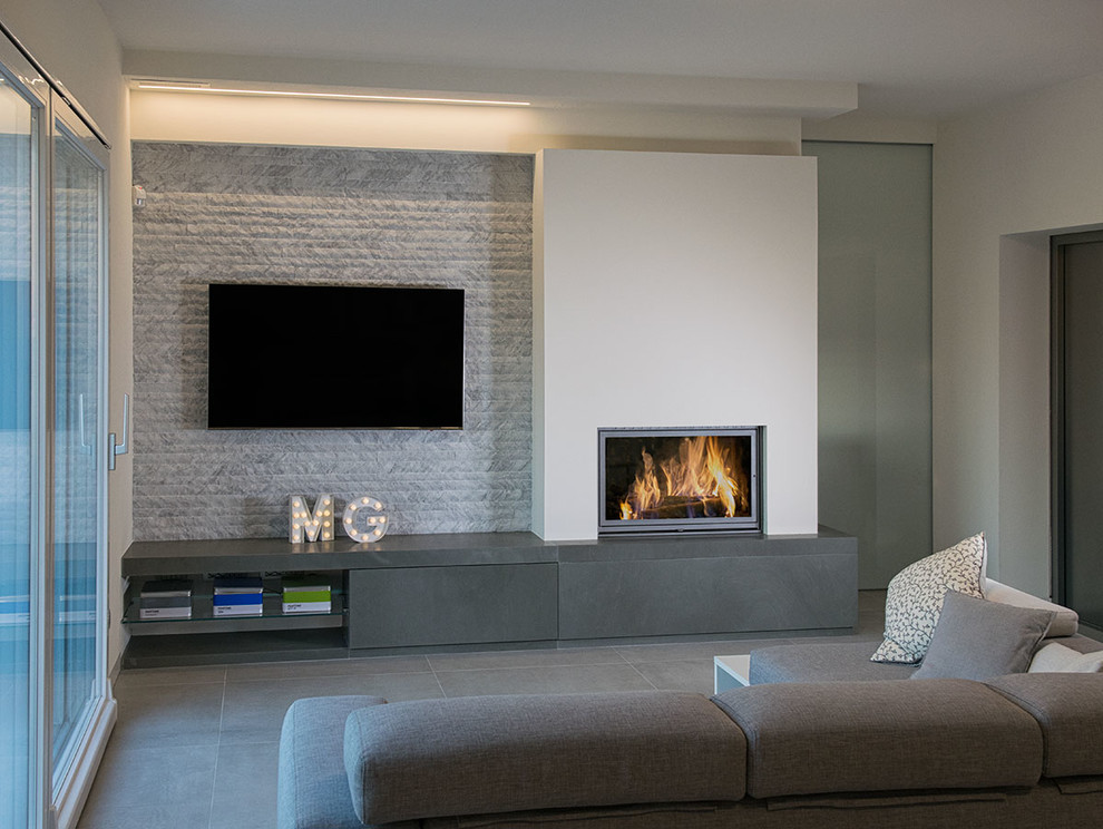 Diseño de salón contemporáneo con paredes blancas, suelo de baldosas de cerámica, chimenea de esquina, marco de chimenea de piedra y televisor colgado en la pared