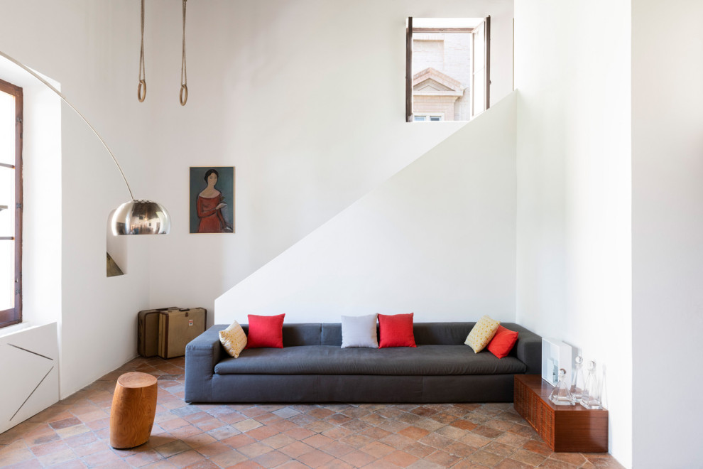 Modelo de salón abierto mediterráneo extra grande sin televisor con paredes blancas, suelo de baldosas de terracota y suelo rojo