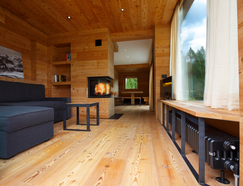 中くらいなラスティックスタイルのおしゃれなリビング (茶色い壁、無垢フローリング、両方向型暖炉、木材の暖炉まわり、内蔵型テレビ、茶色い床) の写真