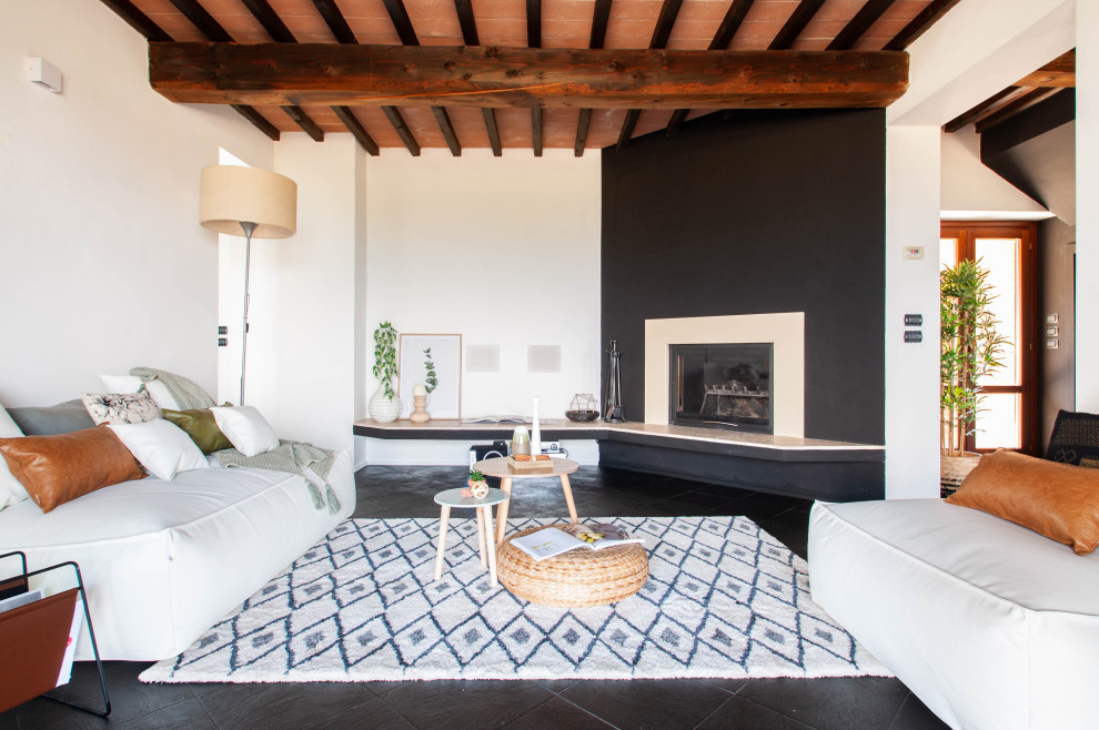 Modelo de salón abierto mediterráneo con paredes blancas, chimenea de esquina y suelo negro